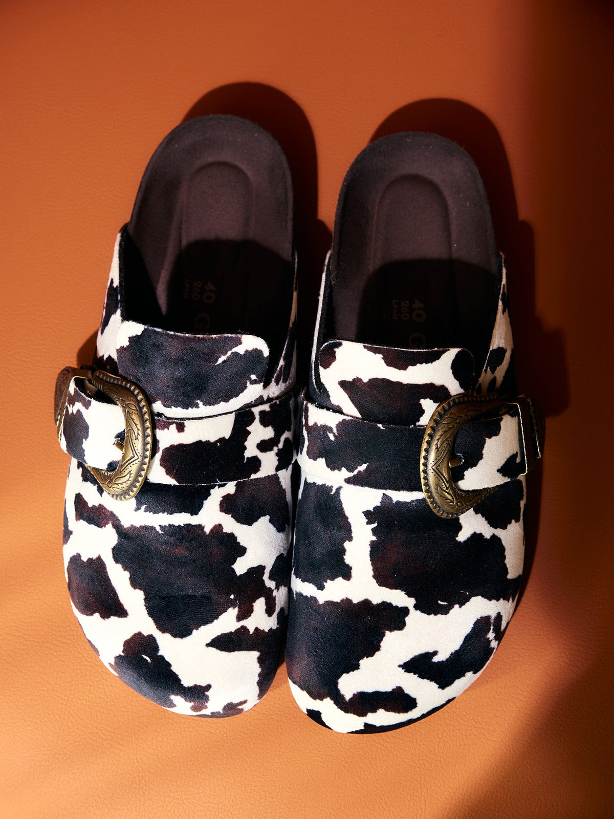 A pair of Genuins Huma clogs in a black and white cow print